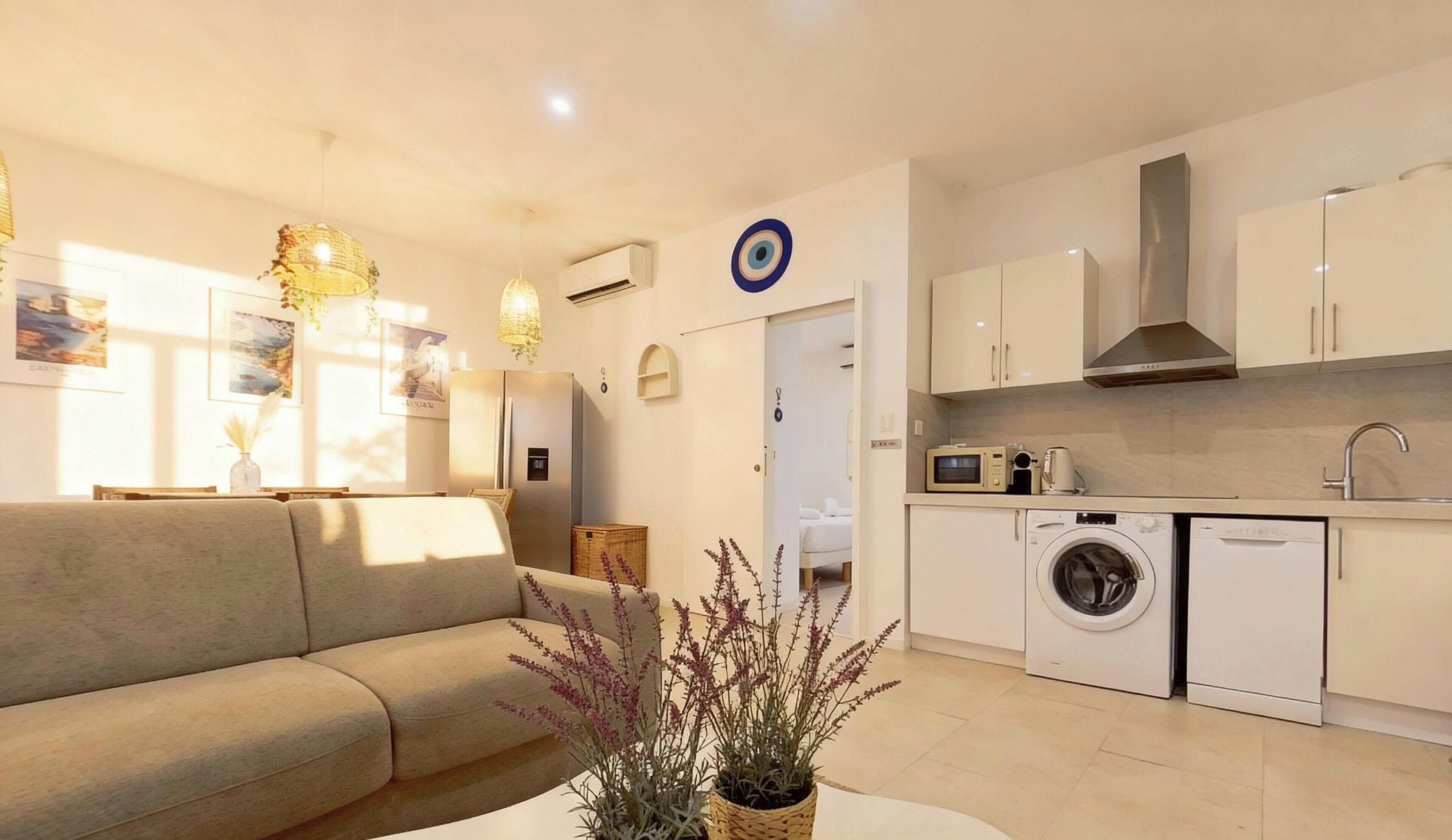 A modern apartment with a living room, kitchenette, and a washing machine.