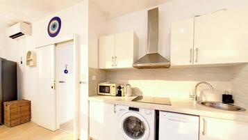 A compact kitchen with a washing machine, microwave, and a sink.