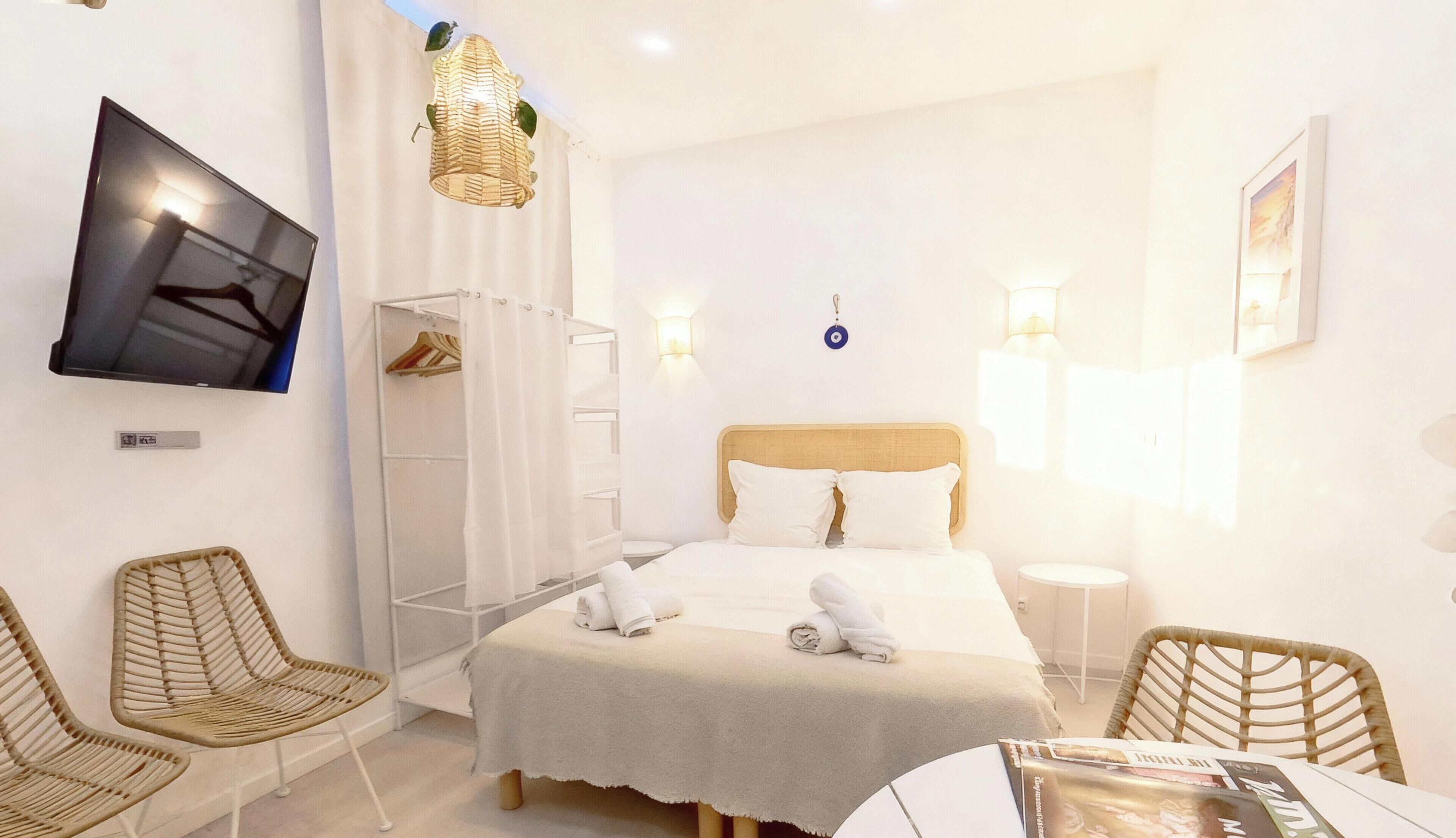 Una camera d'albergo con un letto, una televisione, un armadio e due poltrone in vimini.