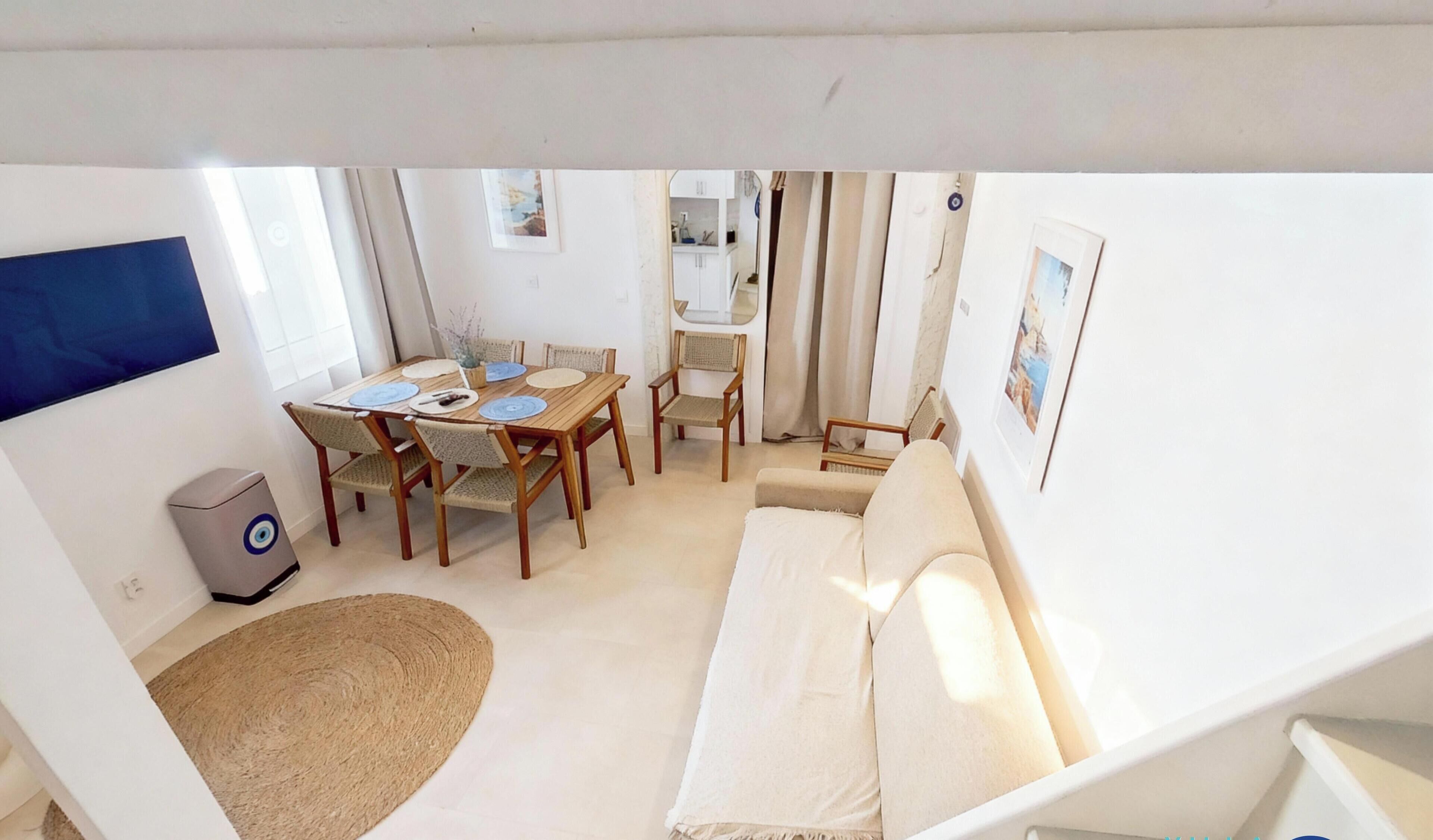 A compact living space with a dining area, a sofa, and a small kitchenette.