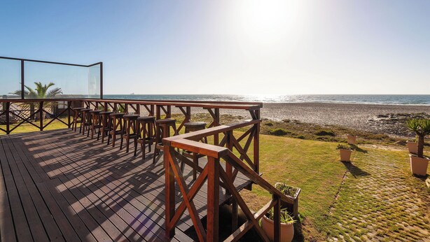 Una terraza de madera con asientos al aire libre con vista a una playa.