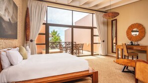 Un dormitorio con una cama grande, un escritorio, una silla, un ventanal y vistas al exterior.