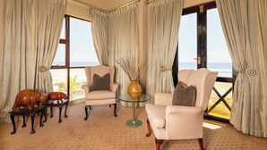 Una habitación con dos sillones, una mesita y vista a la playa.