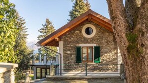 Un edificio de piedra con techo de madera, una ventana circular y contraventanas verdes.