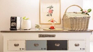 Mostrador de estilo vintage con un letrero que dice "Café de l'Ocean", que incluye una radio, un jarrón con una planta, una obra de arte floral enmarco y una cesta de mimbre con flores.