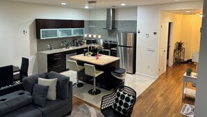 A modern kitchen with a central island, dark cabinetry, and a stainless steel refrigerator. - Posh 2BR/2BA King Bed! Free Parking! 30 Min to NYC

 (East Orange)