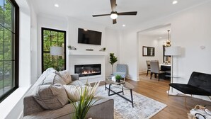 Un salon moderne avec une cheminée, un canapé, une table basse et un téléviseur fixé au mur.