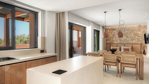 Een moderne keuken met een groot eiland, een eetgedeelte met rieten stoelen en een accentmuur van steen.