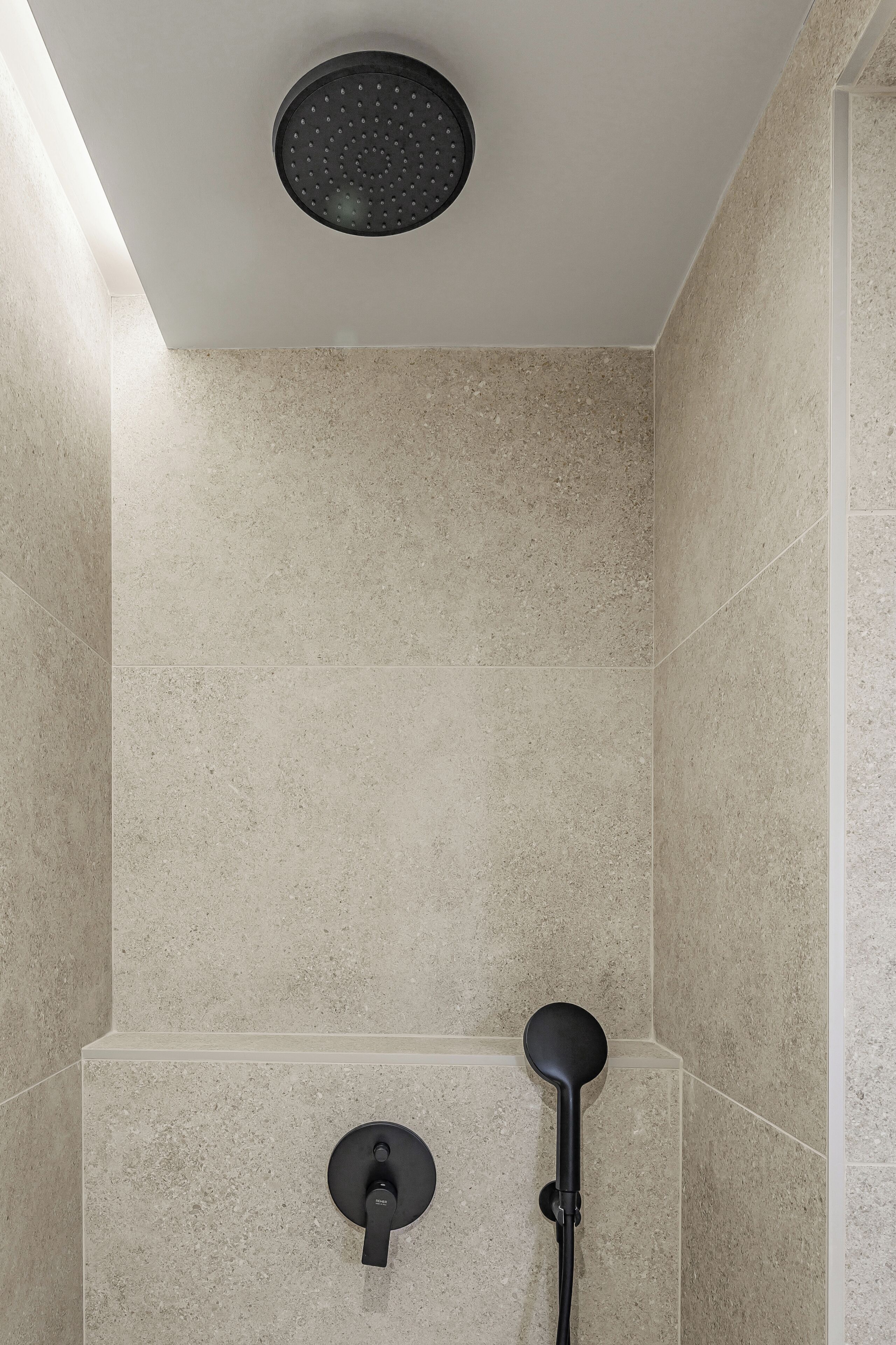 A modern shower with a roundhead showerhead and a handheld shower attachment.