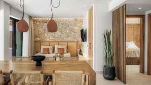 Een moderne eethoek met een houten tafel, rieten stoelen, een accentmuur van steen en een grote potplant.