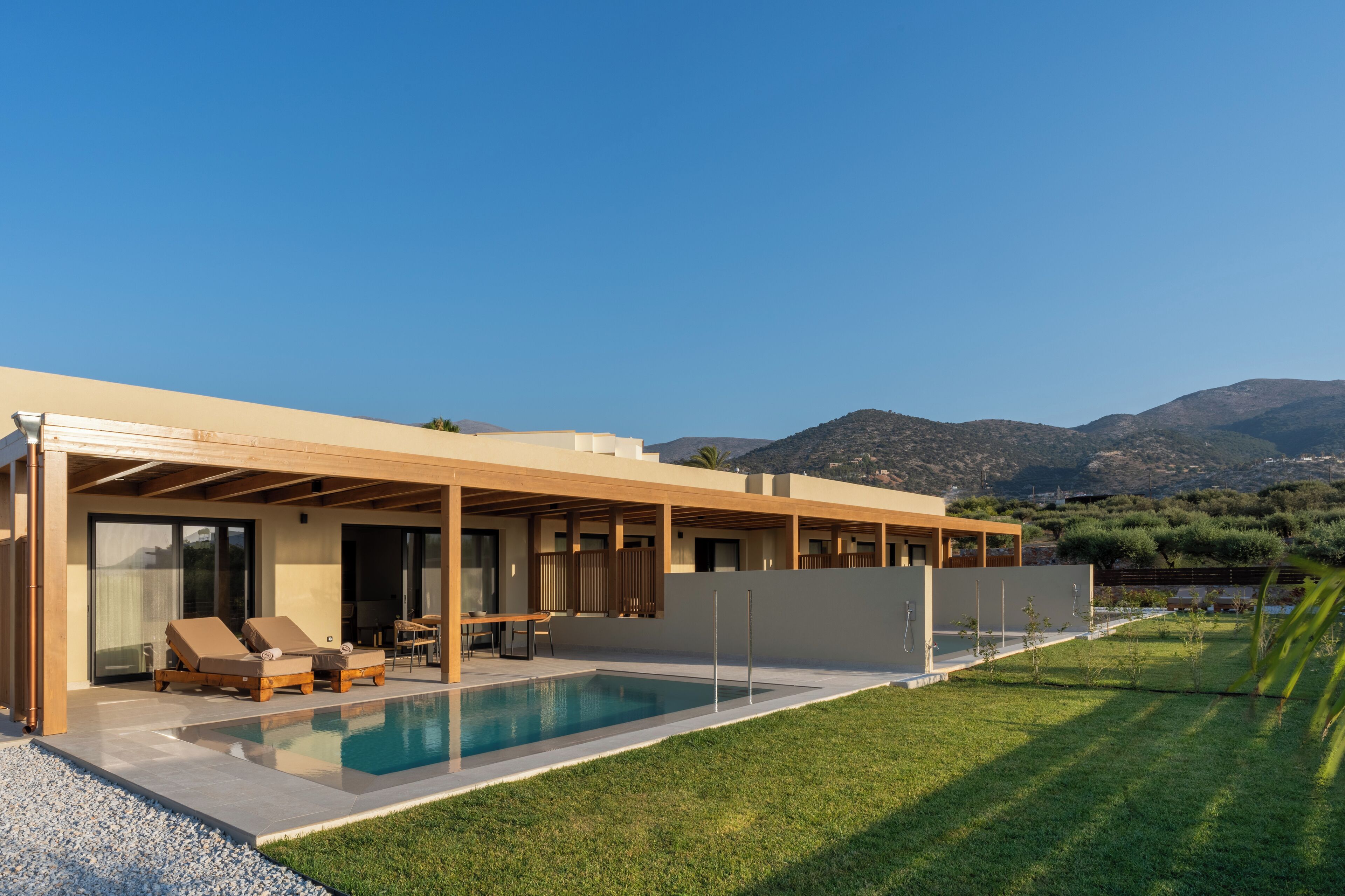 Une maison moderne dotée d’une piscine, d’un espace salon extérieur et offrant une vue sur les montagnes.