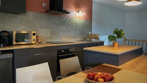 Una cocina moderna con microondas integrado, cafetera y zona de comedor con mesa dispuesta para dos.