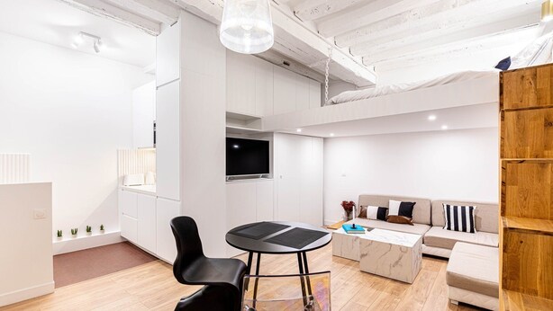 Un salon moderne comprenant un canapé, une table basse, un téléviseur et un coin repas avec des chaises et une table.
