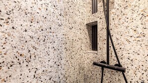 Une salle de bain avec un sol en terrazzo, une petite fenêtre et un porte-serviettes.