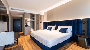 Ein modernes Hotelzimmer mit einem großen Bett, einem Schreibtisch und einem begehbaren Kleiderschrank.