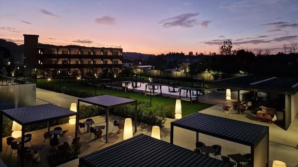 Eine Außenpatio-Terrasse mit Tischen, Stühlen, einem Pool und einem Gebäude im Hintergrund.