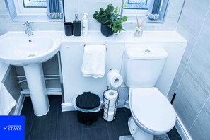 Ein modernes Badezimmer mit Waschbecken, Toilette und einer kleinen Mülleimer.