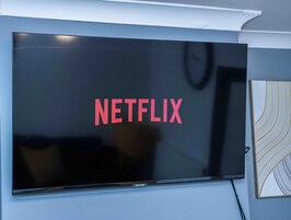 A flat-screen TV mounted on a wall with the Netflix logo displayed on its screen.