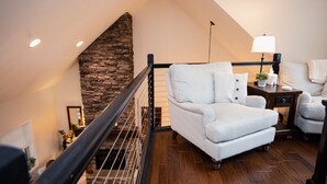 En hyggelig stue med en stenpejs, en stribet sofa og et lille sofabord med en lampe.