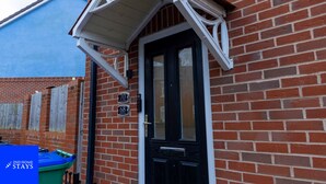 A black door with a white porch and a brick wall. - 2ndhomestays-west Bromwich- 2-bedroom Maisonette (West Bromwich)