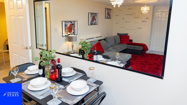 A dining area with a table set for four, a large mirror reflecting the room, and a red carpet leading to a seating area. - 2ndhomestays-west Bromwich- 2-bedroom Maisonette (West Bromwich)