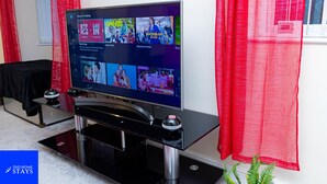 A flat-screen TV mounted on a black stand with a decorative item on top. - 2ndhomestays-west Bromwich- 2-bedroom Maisonette (West Bromwich)