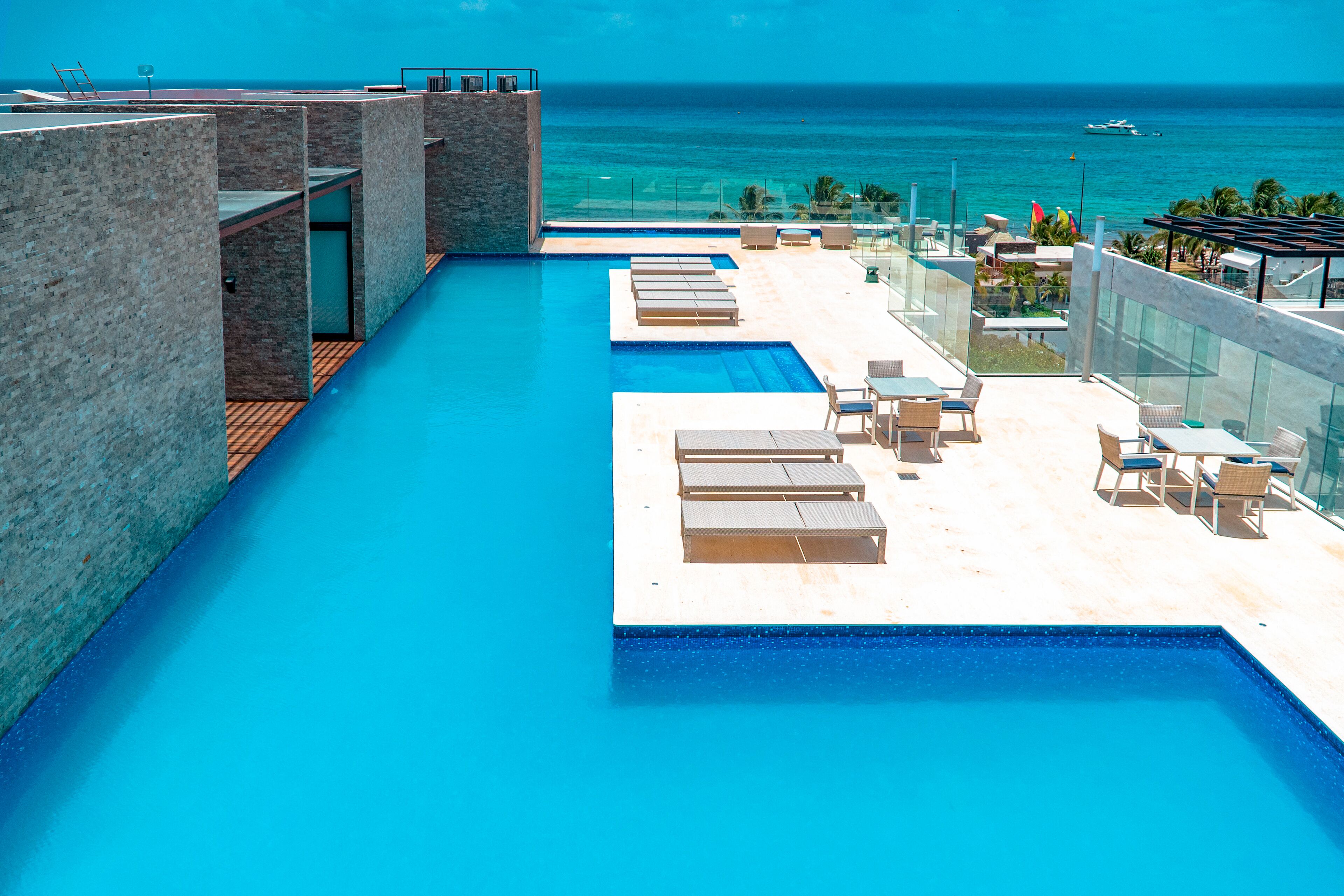 A rooftop infinity pool with lounge chairs and a view of the ocean.