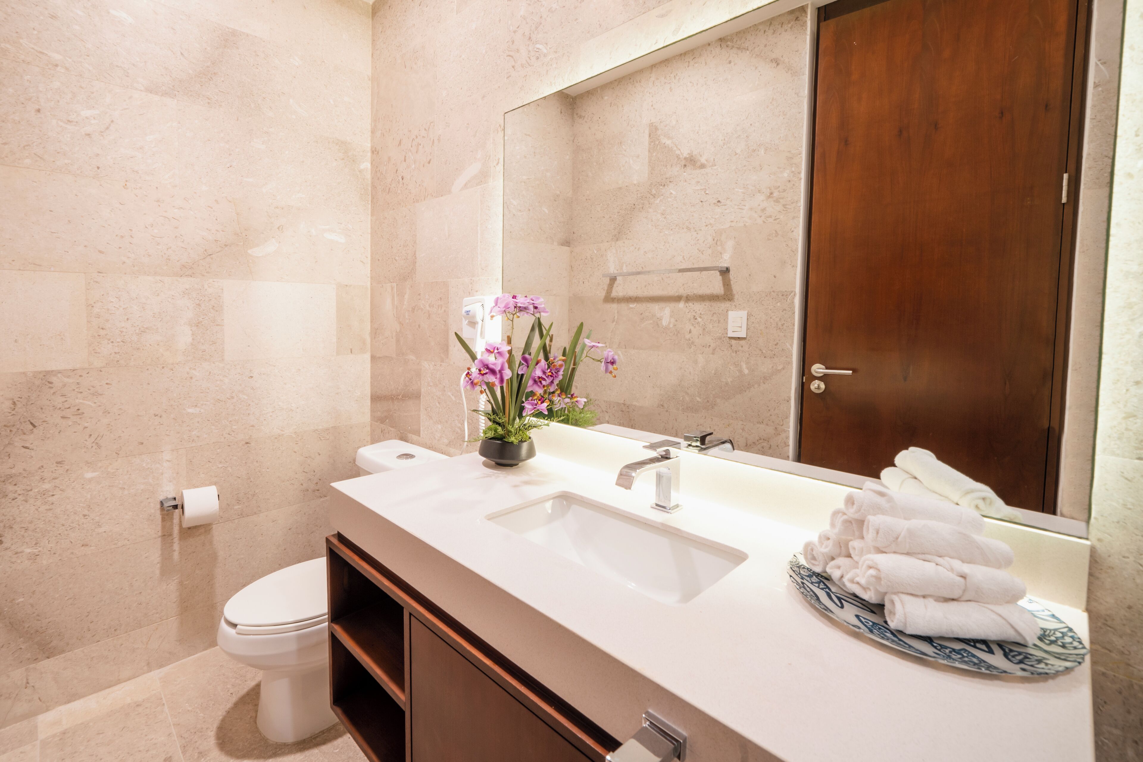 Une salle de bain avec un double lavabo, un miroir, des toilettes et un porte-serviettes.
