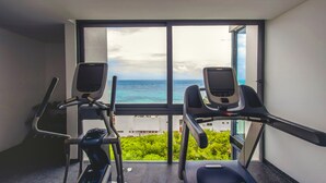 A gym with two treadmills and a stationary bike, overlooking a scenic view of the ocean and greenery. - Maricruz - Luxury Condo with Jacuzzi (Playa del Carmen)