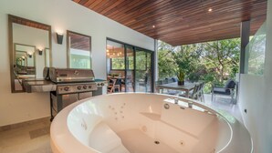 A modern bathroom with a large bathtub, a wooden ceiling, and a grill outside the window. - Maricruz - Luxury Condo with Jacuzzi (Playa del Carmen)