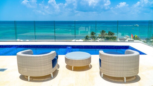 A poolside area with wicker furniture and a view of the ocean. - Maricruz - Luxury Condo with Jacuzzi (Playa del Carmen)
