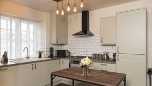 Una cucina moderna con mobili bianchi, un'isola centrale e un piano cottura nero.