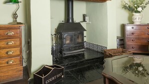 Un tradizionale stufa a legna in una cucina con un mobile in legno e un cesto di vimini.