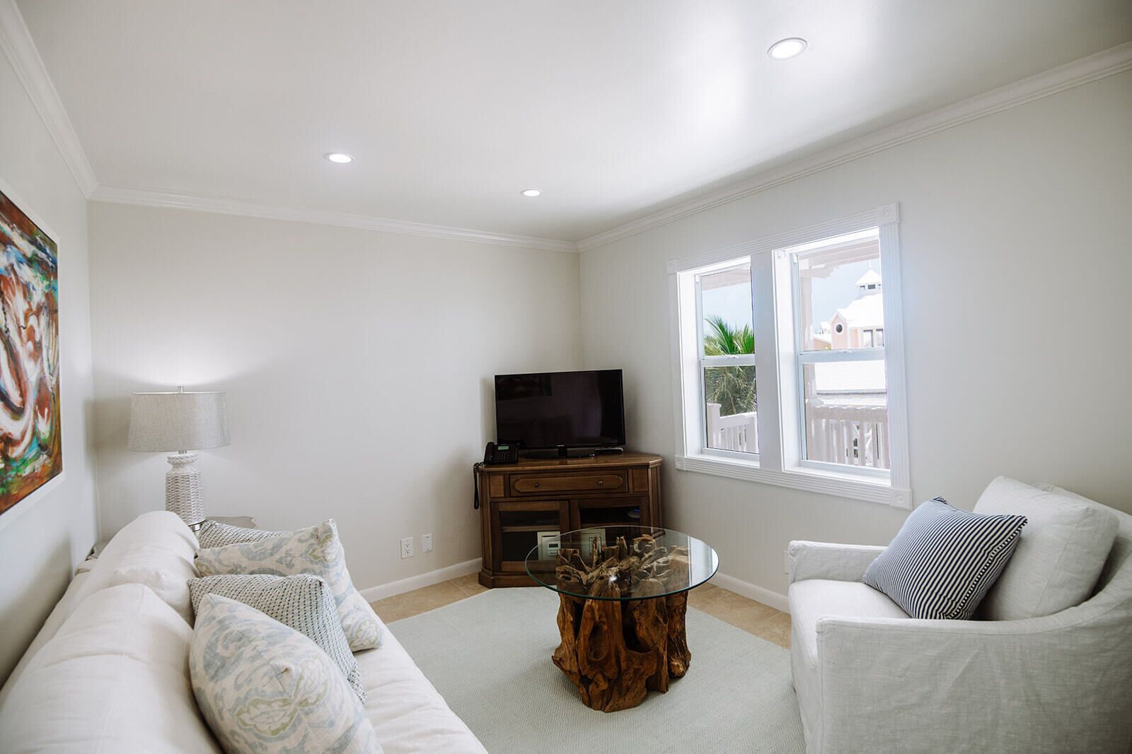 A living room with a sofa, a coffee table, a TV, and a window with a view.