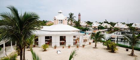 A beachside resort with a central white pavilion, a lighthouse, and a marina.
