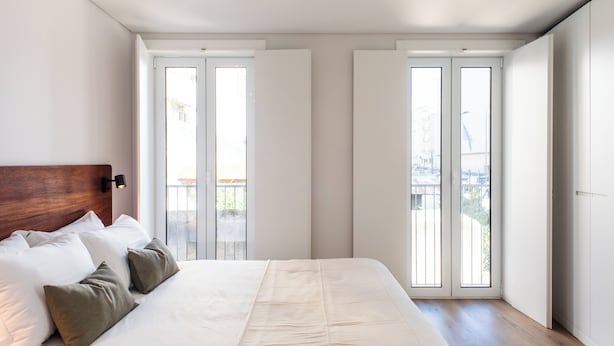 Une chambre moderne avec un grand lit, deux portes coulissantes et une vue sur l’extérieur.