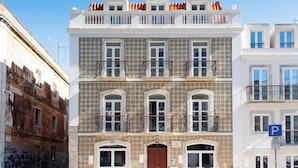 Un immeuble à plusieurs étages, doté d’une façade recouverte de carreaux, de balcons et d’une entrée au niveau du sol.
