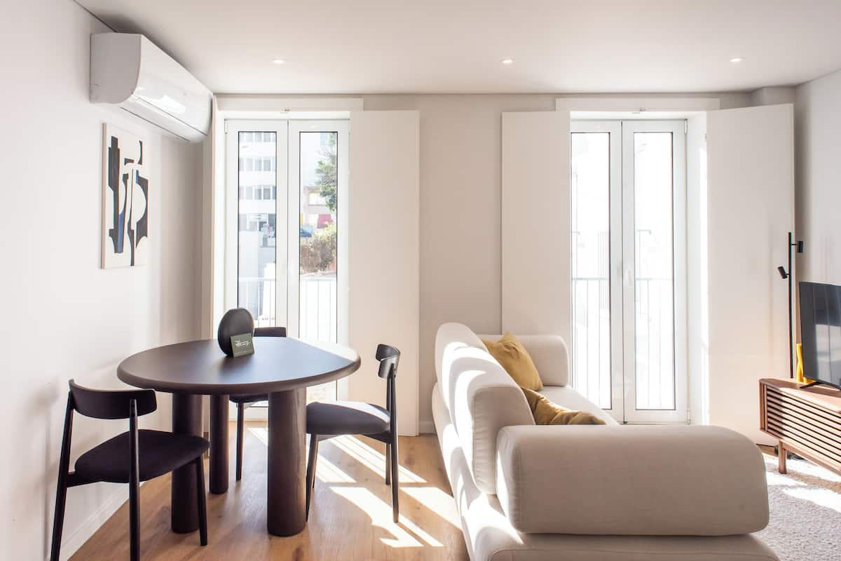 Un salon moderne avec une table de salle à manger ronde, deux chaises, un canapé et un meuble pour la télévision.