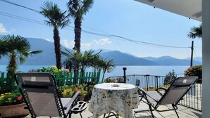 An outdoor seating area with two chairs and a table, overlooking a body of water and mountains.