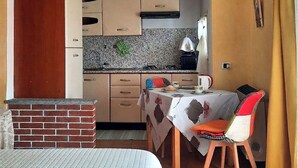 A compact kitchen with a sink, stove, and a small dining area with a table and chairs.