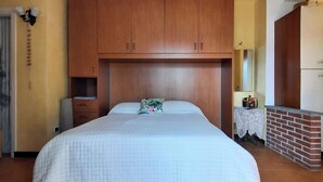 A bedroom with a large bed, wooden wardrobe, and a small table with a mirror.