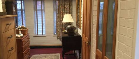 A narrow hallway with a wooden dresser, a small table with a lamp, and a bench.