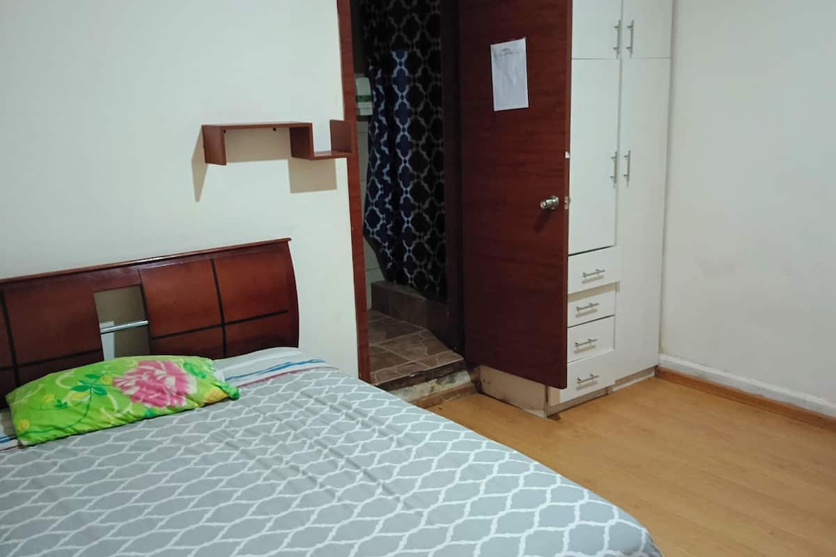 A bedroom with a bed, a wardrobe, and a door leading to a bathroom.