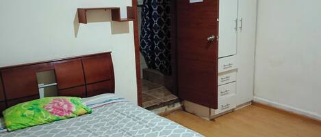 Un dormitorio con cama, armario y puerta que da a un baño.