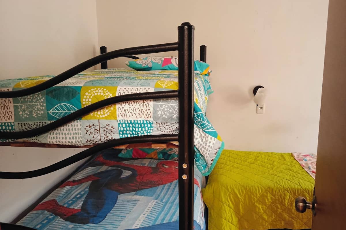 A bunk bed with a patterned quilt and a yellow blanket.