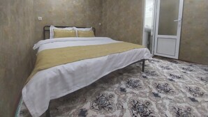 A bedroom with a bed, a door, and patterned carpet.