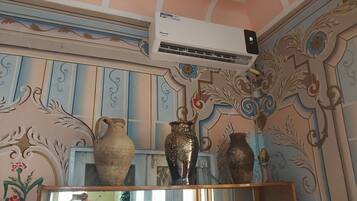 A room with decorative wall panels, a large air conditioning unit, and a bookshelf with books.