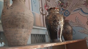 A shelf with three vases of varying sizes and designs.