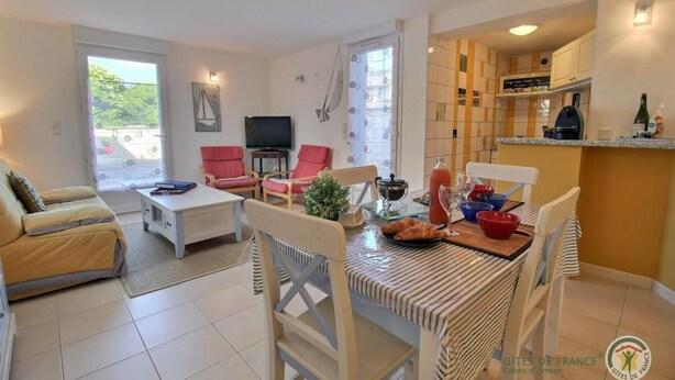 A living room with a sofa, a TV, and a dining area with a table and chairs. - Gîte la Crabière, 900m de la Mer, Animaux de Compagnie Bienvenue (SAINT CAST le guildo)