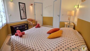 A hotel room with a bed, a chair, a desk, and a lamp. - Gîte la Crabière, 900m de la Mer, Animaux de Compagnie Bienvenue (SAINT CAST le guildo)